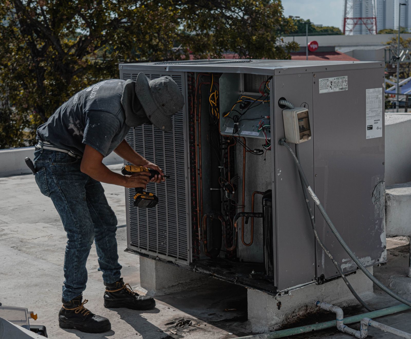 HVAC technician repairing an outdoor air conditioner on a rooftop in daylight